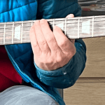 Mano sobre el mástil de una guitarra