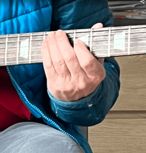 Mano sobre el mástil de una guitarra